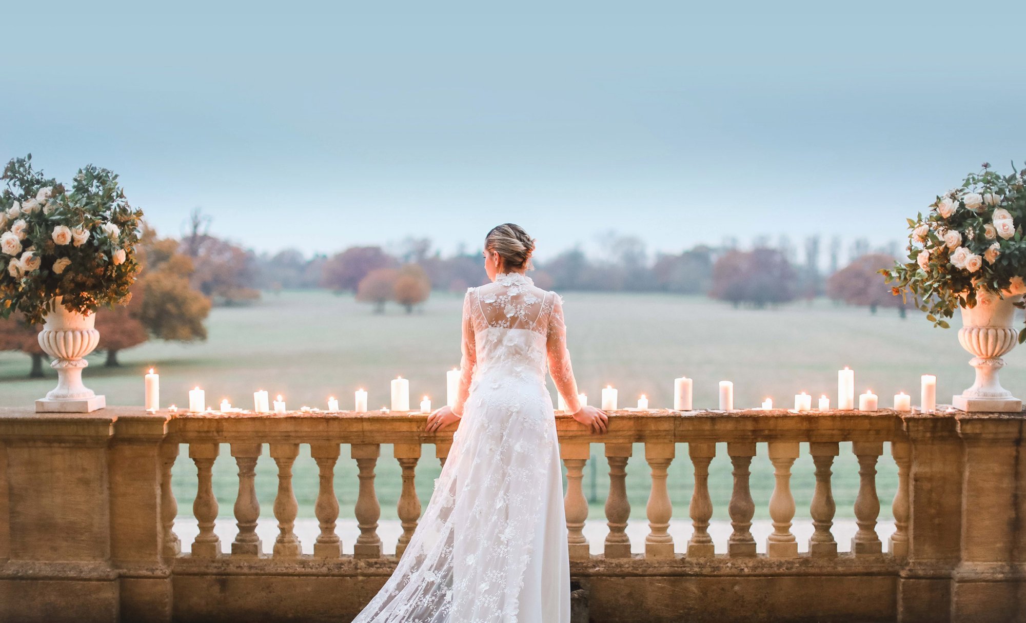 Bride looks out to countryside from balcony at Kirtlington Park