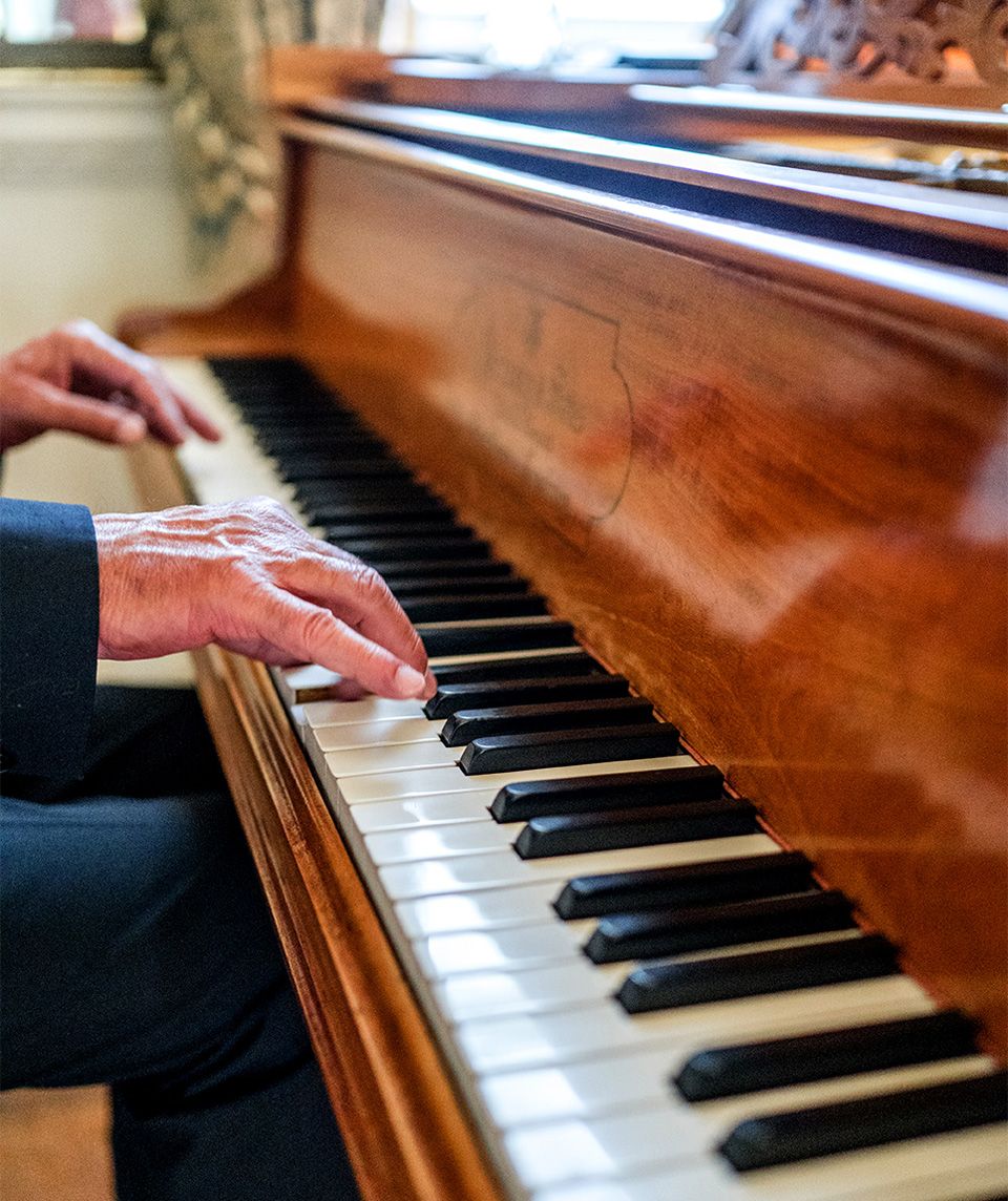 A pianist plays within the elegant country house rooms at Kirtlington Park