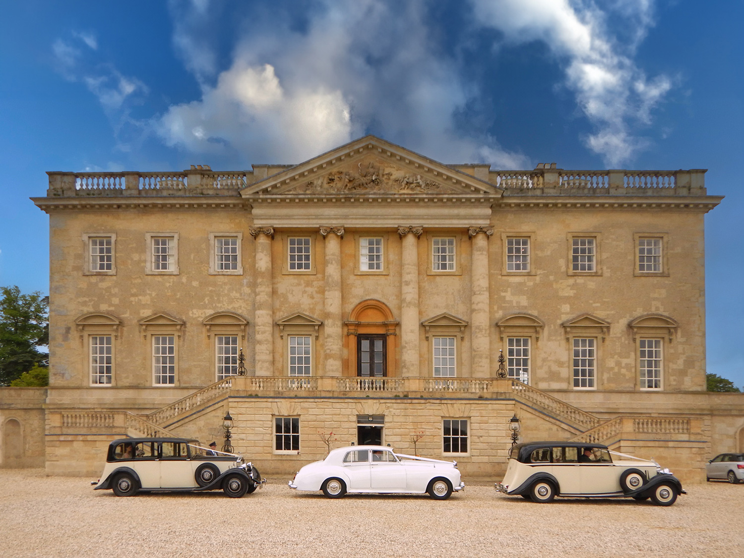 Classic cars compliment the classical architecture of Kirtlington Park for an elegant wedding